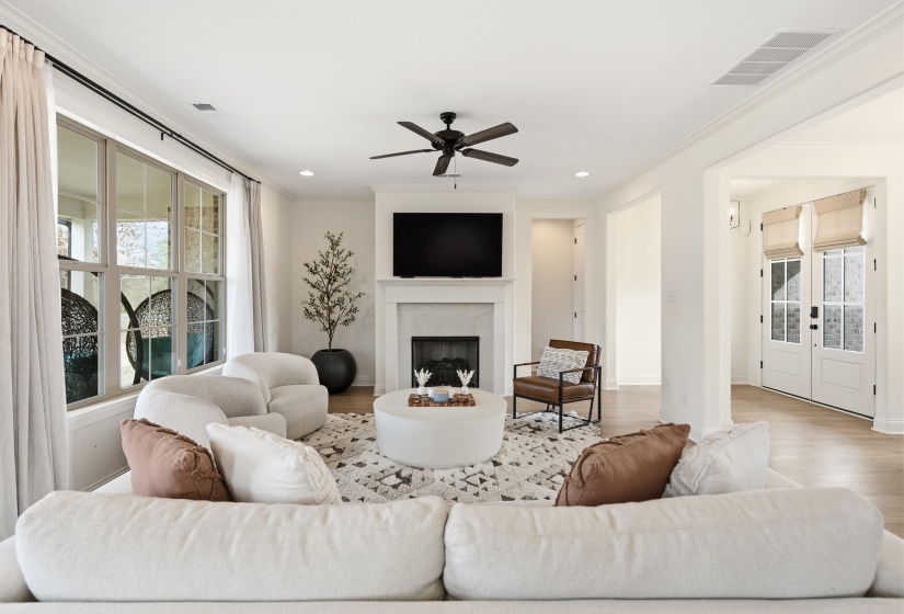 Living area with a ceiling fan, wood finished floors, crown molding, a premium fireplace, and recessed lighting