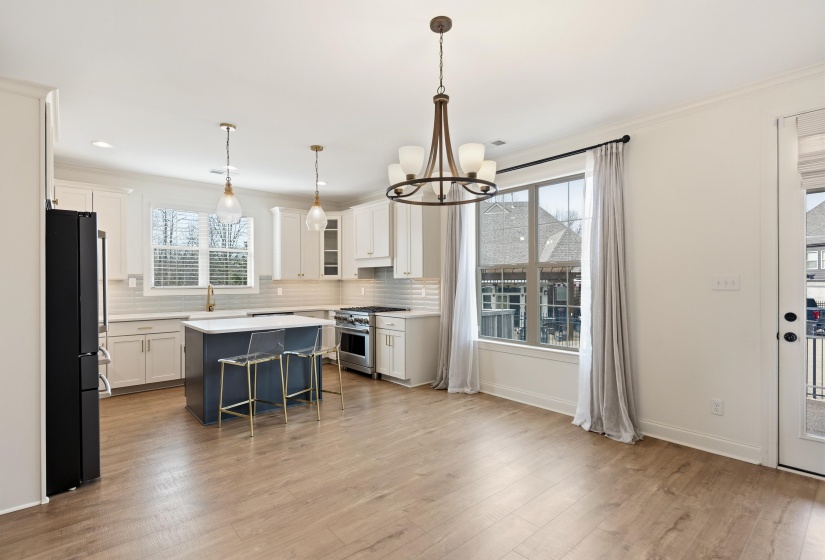 Dual tone kitchen with a kitchen breakfast bar, two tone cabinetry, freestanding refrigerator, stainless steel range, and glass fronted cabinets
