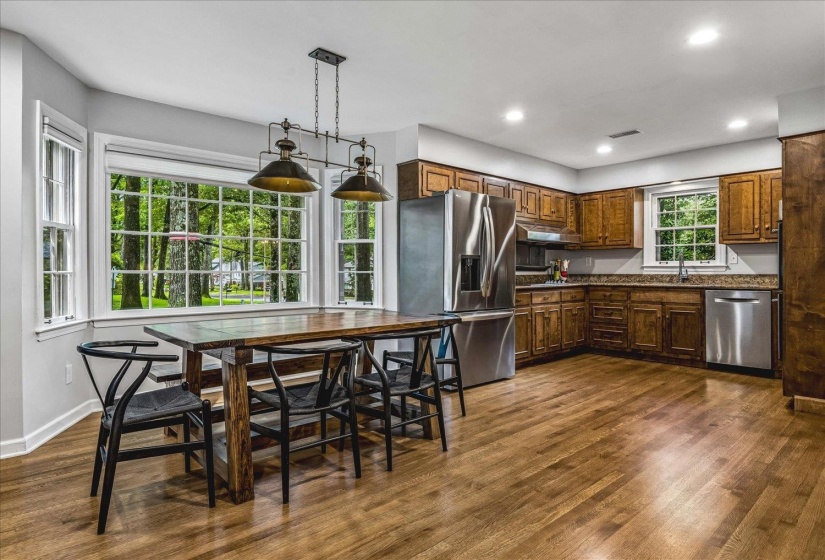 Open-concept kitchen with wood-finish flooring, recessed lighting, and a bay window