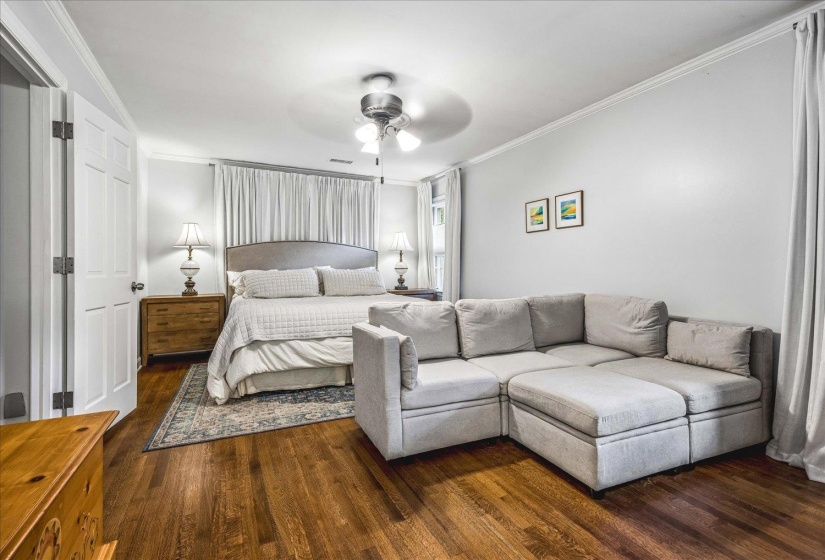 Hardwood flooring throughout featuring a ceiling fan, crown molding, and white interior doors