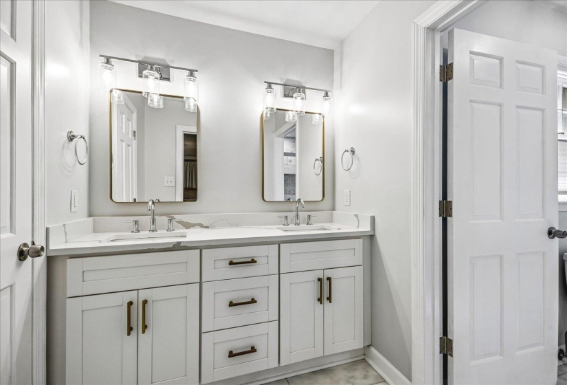 Dual vanity with white cabinetry, modern brass hardware, and a white countertop
