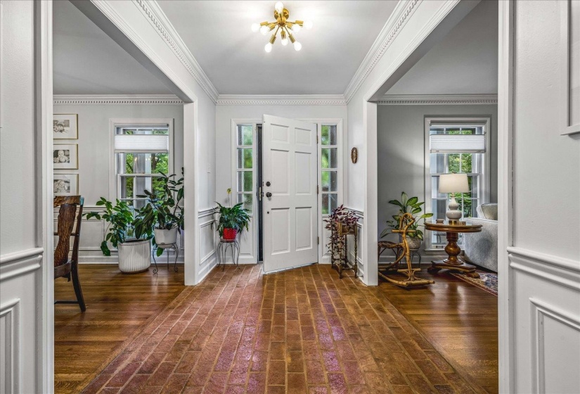 Entryway featuring brick flooring, a white paneled front door with sidelights, and a brass Sputnik-style chandelier