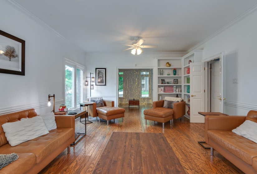 Bright living area featuring wood-finish flooring, white walls, and built-in shelving
