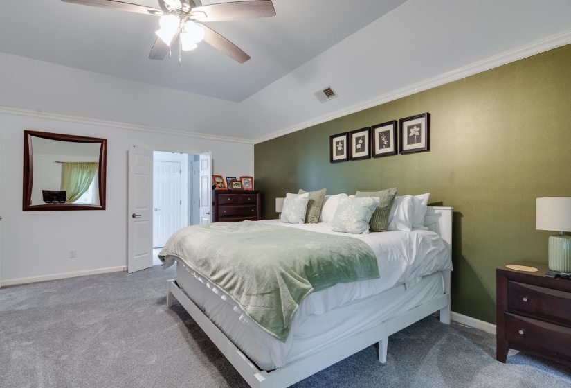 Bedroom featuring a tray ceiling, ceiling fan with light fixture, and a single accent wall