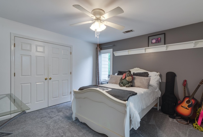 Bedroom featuring gray carpet flooring, white paneled bifold closet doors, a ceiling fan with integrated lighting, and a window with white trim