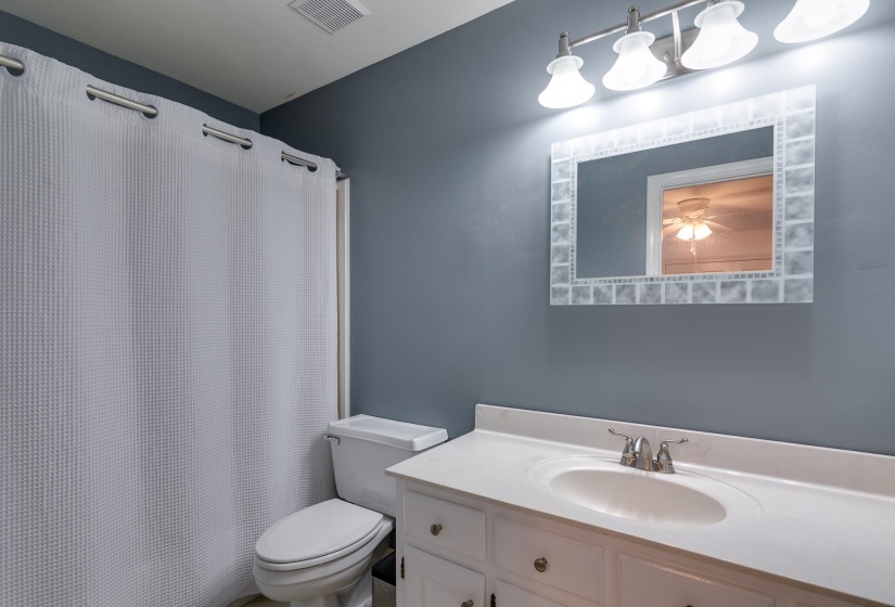 Bathroom featuring a white vanity with an integrated sink, brushed nickel faucet, and under-sink storage