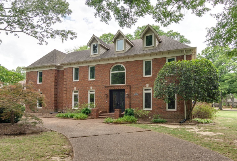 Brick-clad exterior with a prominent arched window, multiple dormer windows, and a dark double-door entry