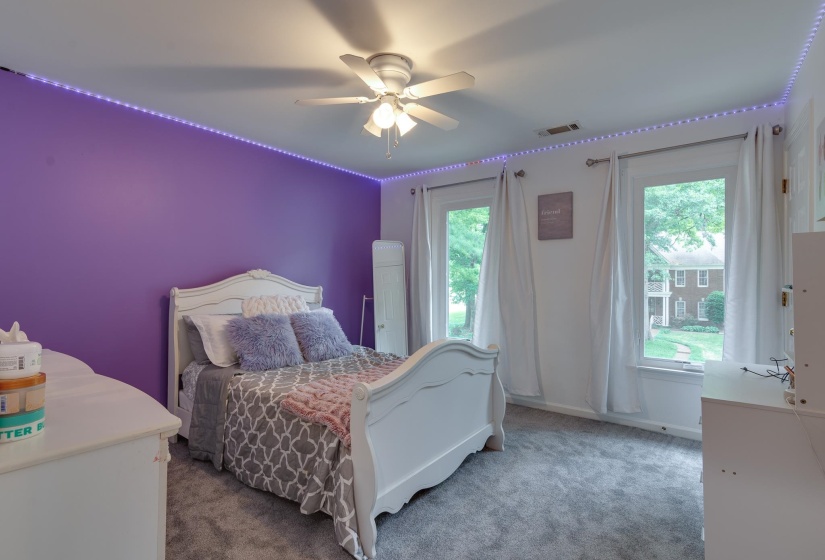 Bedroom featuring two large windows, ceiling fan, and wall-to-wall carpeting