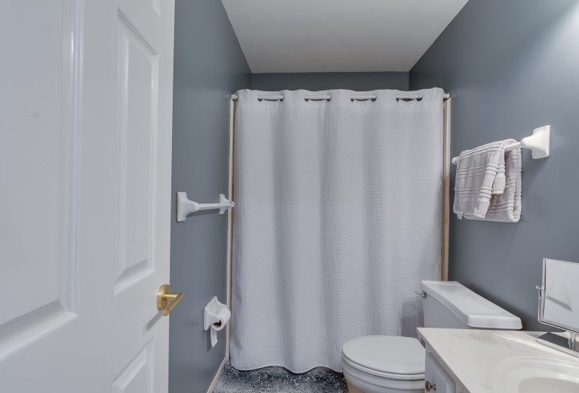 Full bathroom featuring a white toilet, light-colored vanity with an integrated sink, and a shower area with a white shower curtain