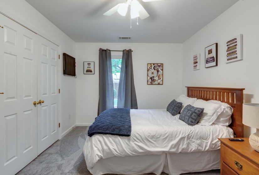 Bedroom featuring plush carpeting, a ceiling fan with integrated lighting, and white bi-fold closet doors with brass hardware