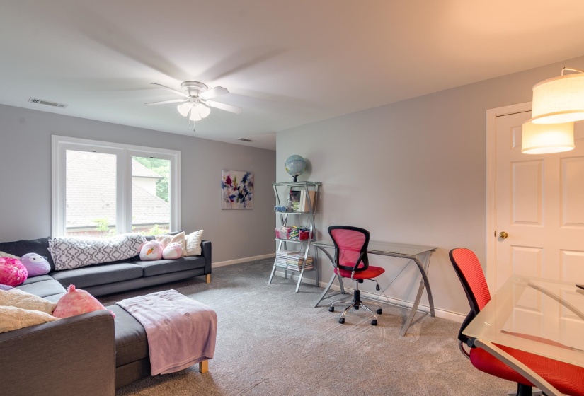 Carpeted room featuring a ceiling fan, dual-pane window, and a white paneled door