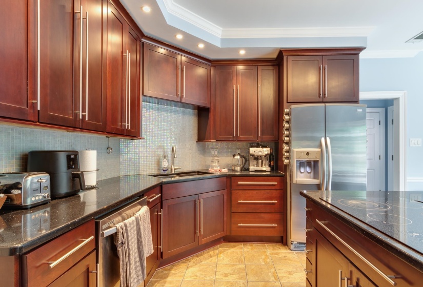 Kitchen featuring dark wood cabinetry, a tiled backsplash, dark speckled countertops, stainless steel appliances, and tile flooring