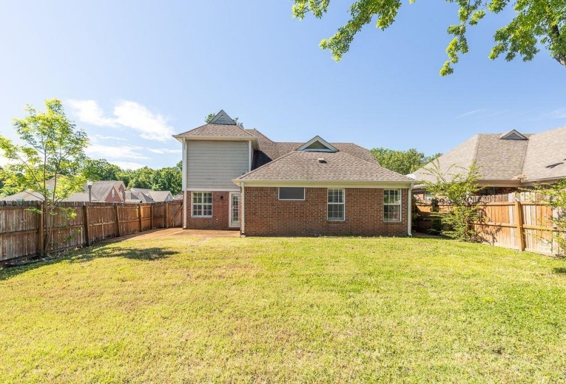 Expansive backyard featuring a manicured lawn, a full privacy fence, and a brick and siding exterior
