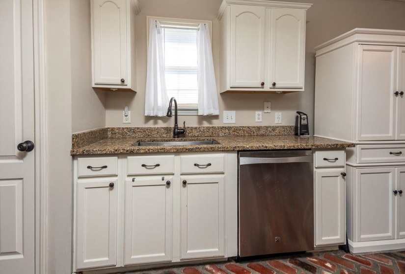 Kitchen area featuring white cabinetry, a stainless-steel dishwasher, and a dark bronze faucet