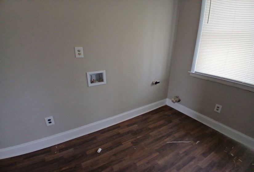 Utility area featuring wood-finish flooring, light neutral wall paint, and white trim molding