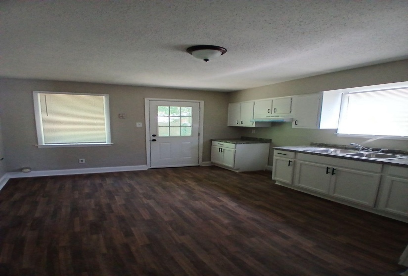 Spacious kitchen featuring wood-finish flooring, white cabinetry, a double basin stainless steel sink, and light-colored countertops