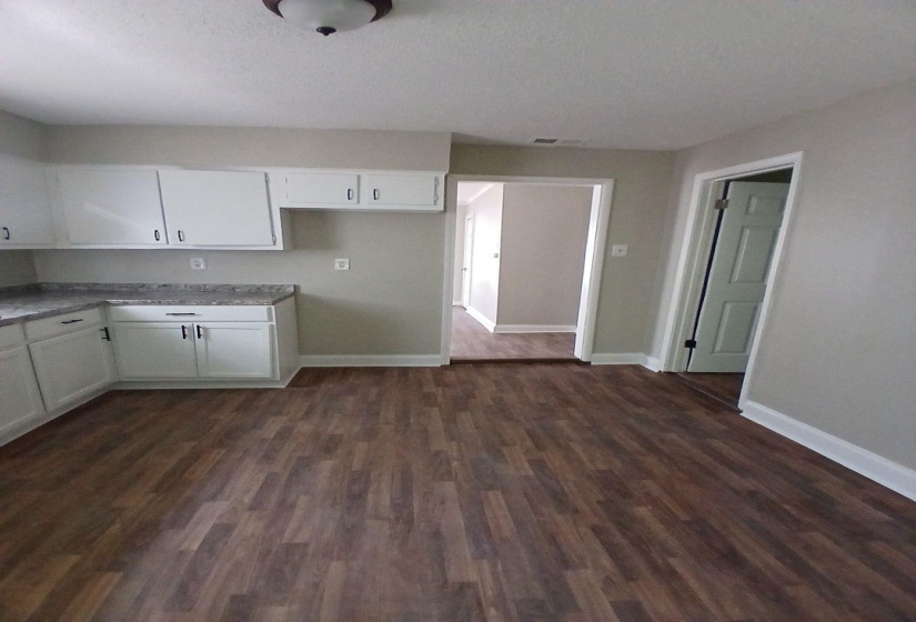 Kitchen featuring wood-finish flooring and white cabinetry