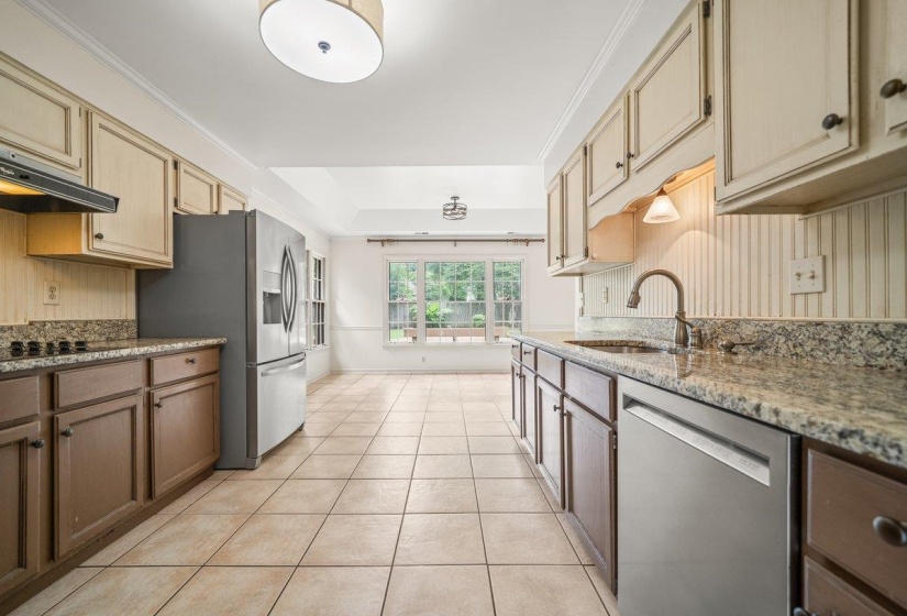 Spacious kitchen featuring tile flooring, granite countertops, and two-tone cabinetry