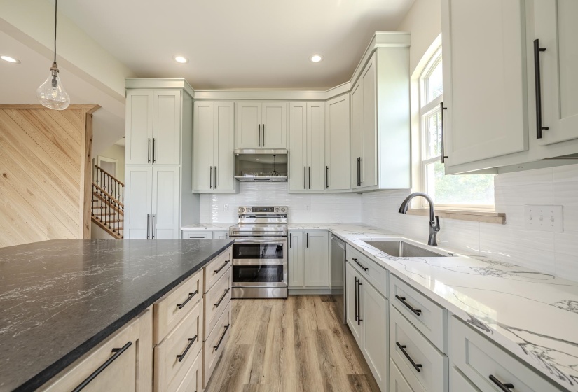 Kitchen featuring a large island with a dark stone countertop, light wood-finish cabinetry, stainless steel appliances, and white subway tile backsplash