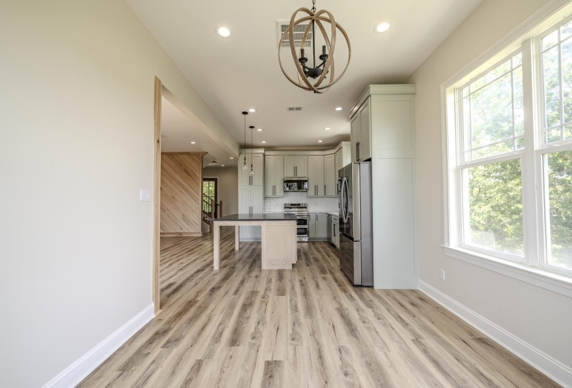 Spacious room with wood-finish flooring, a contemporary chandelier, and large windows