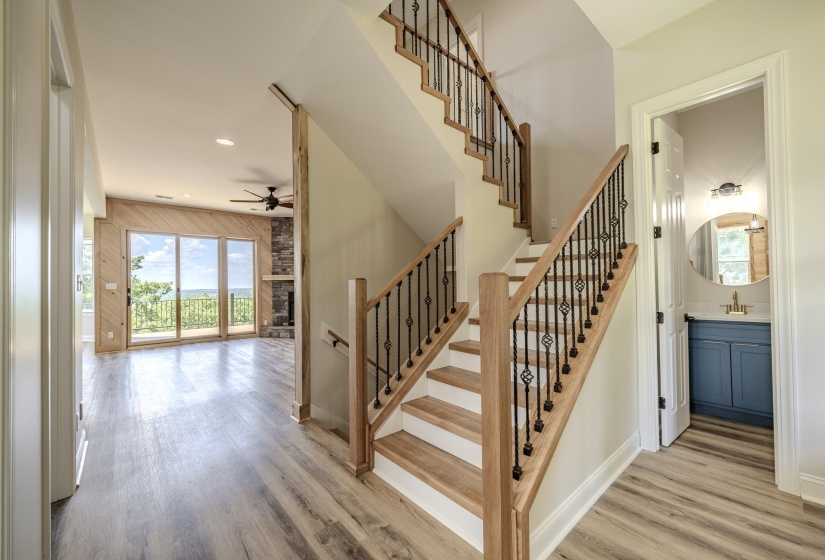 Dual-level staircase featuring wood-finish treads, white risers, and wrought iron balusters