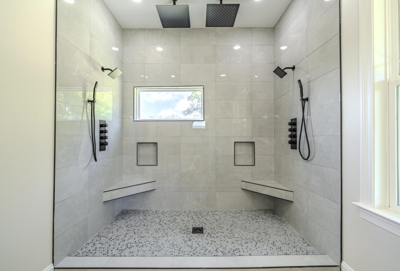 Spacious walk-in shower featuring large format tile walls, dual rainfall showerheads, and matte black fixtures