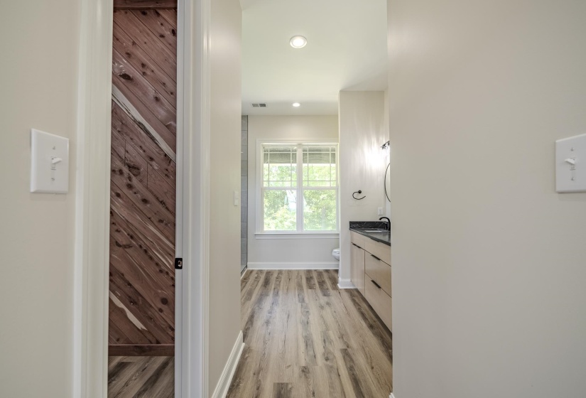 Spacious bathroom featuring wood-finish flooring, a contemporary vanity with a dark countertop, and modern fixtures