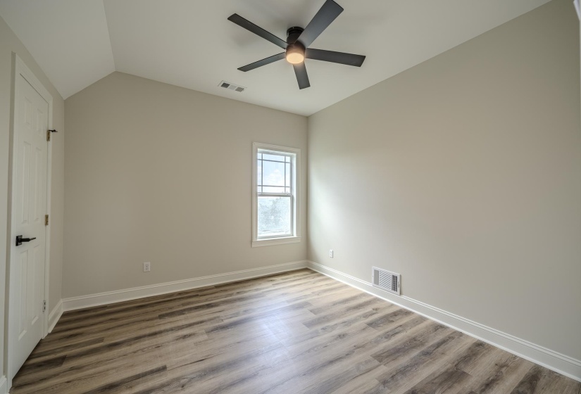 Room featuring vaulted ceilings, wood-finish flooring, a contemporary ceiling fan, and a double-hung window