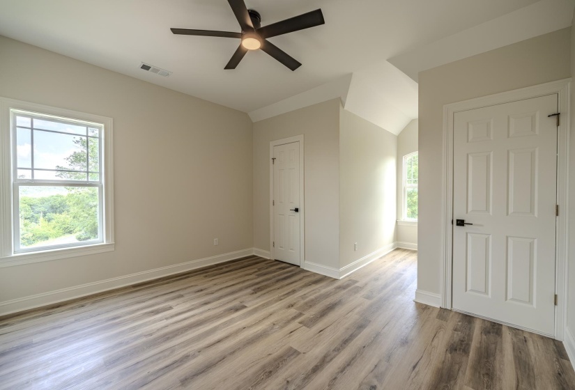 Spacious room featuring wood-finish flooring and a contemporary ceiling fan with integrated lighting