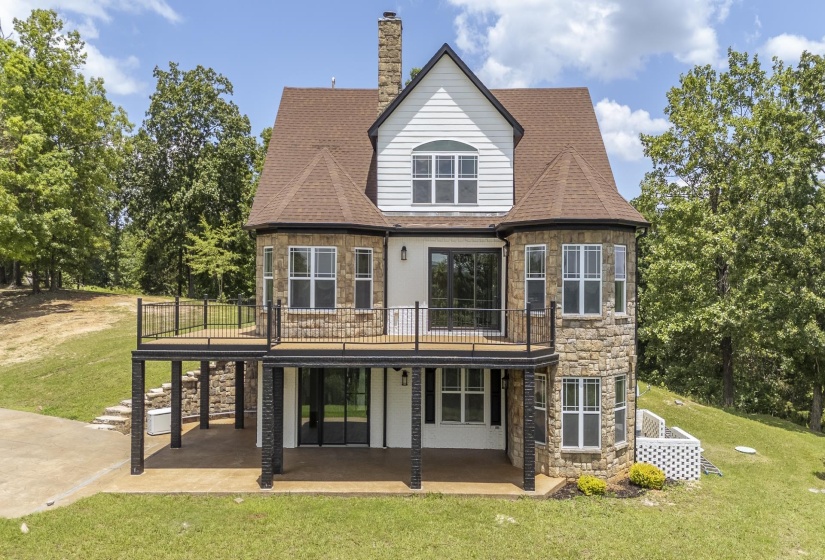 Multi-level residence featuring stone and siding exterior with a prominent second-story deck