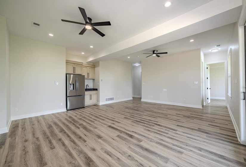 Spacious room featuring wood-finish flooring, recessed lighting, and modern ceiling fans