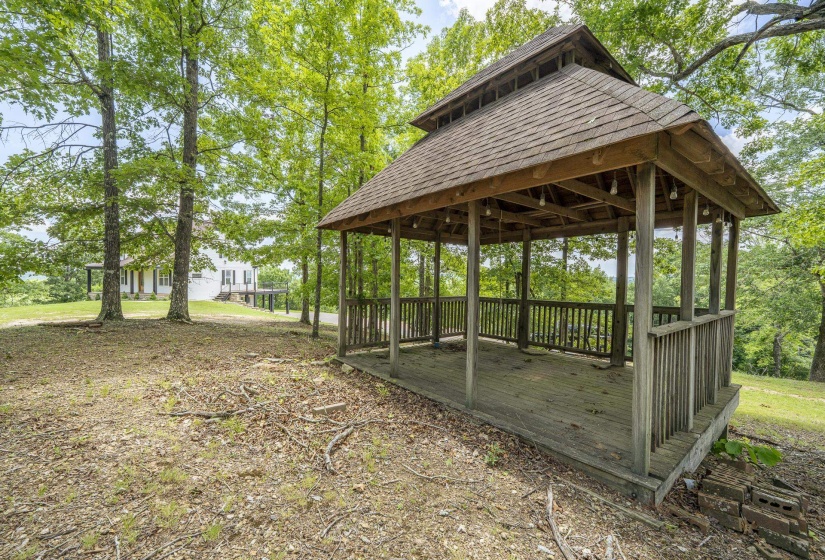 Freestanding gazebo featuring a multi-tiered roof, wood-finish decking, and open-air wood railing
