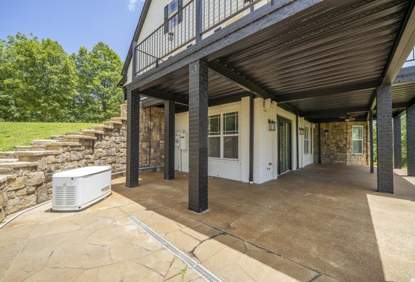 Expansive covered patio featuring a concrete surface, black brick support columns, and recessed lighting
