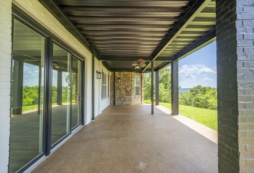 Expansive covered patio featuring a concrete floor, painted brick walls, and black structural columns