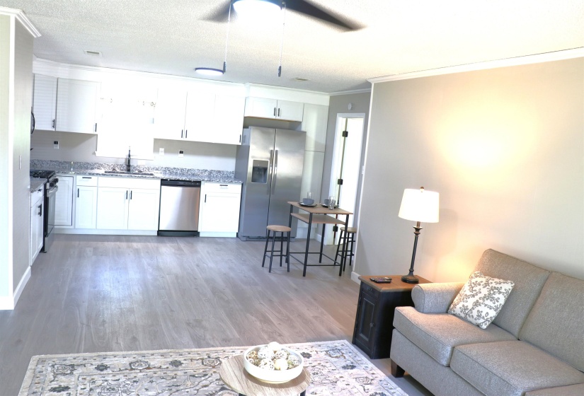 Kitchen with stainless steel appliances, white cabinetry, a ceiling fan, light wood finished floors, and crown molding