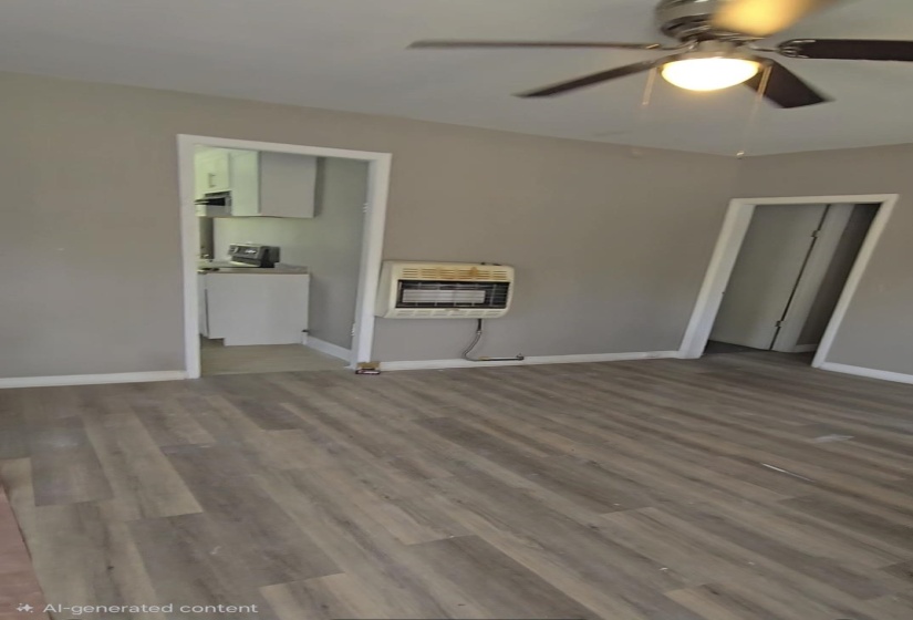 Living area featuring wood-finish flooring, a wall-mounted heater, and a ceiling fan with integrated lighting