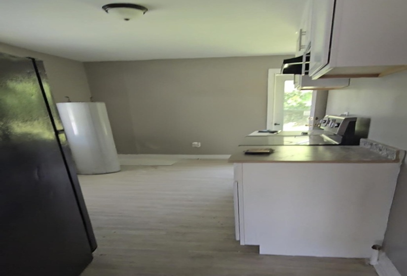 Kitchen space featuring white cabinetry, light-toned wood-finish flooring, and a window providing natural illumination