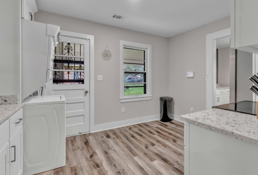 Kitchen area with wood-finish flooring, white cabinetry, and light-toned countertops