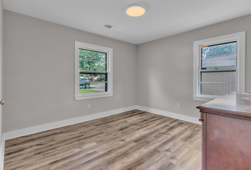 Light gray walls with wood-finish flooring, white baseboards, and window trim
