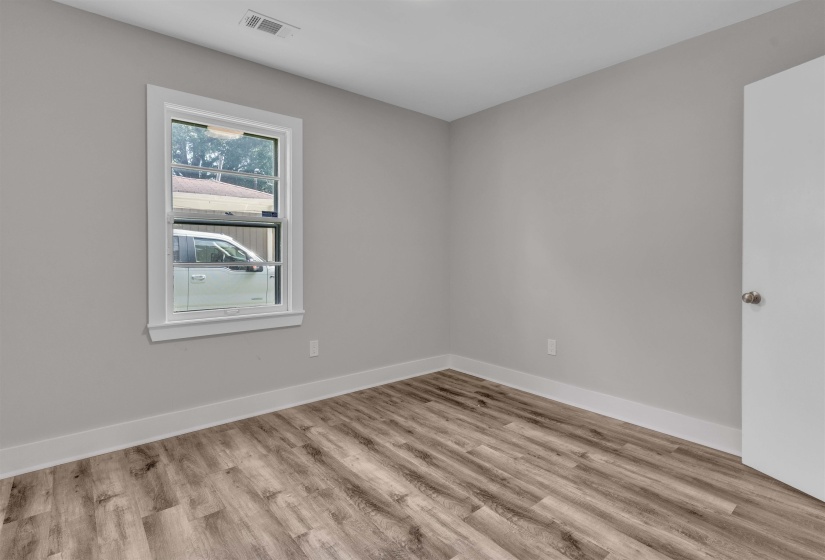 Interior room with wood-finish flooring, light gray wall paint, and white baseboards