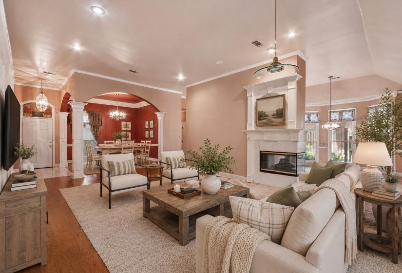 LIVING ROOM (21x17) – Spacious living room with hardwood flooring, custom built-in bookcases and cabinetry, a two-sided gas log fireplace, and a wall of windows that fills the space with natural light. Virtually staged photo.