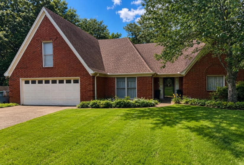 Brick exterior featuring a gabled roofline and attached garage with a panel-style door