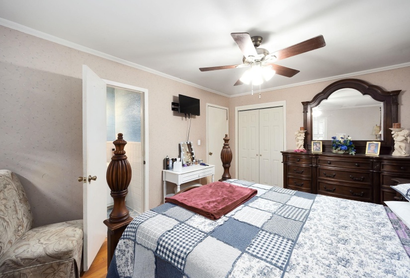 Bedroom featuring wood-finish flooring, a ceiling fan with integrated lighting, and a white bi-fold closet door