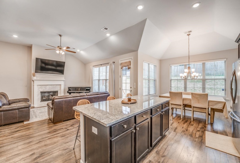 Kitchen featuring dark wood finish cabinets, a kitchen breakfast bar, light stone countertops, lofted ceiling, and light wood-style flooring