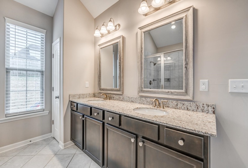 Bathroom with double vanity, a shower stall, and light tile patterned floors