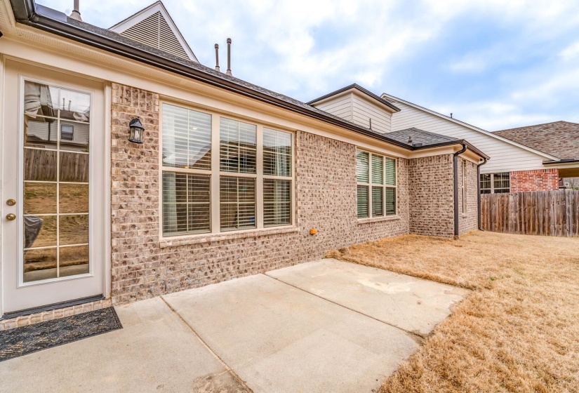 View of exterior entry featuring brick siding and a patio area