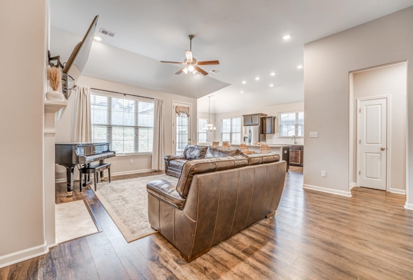 Living room with a ceiling fan, dark wood finished floors, hanging lights, and lofted ceiling