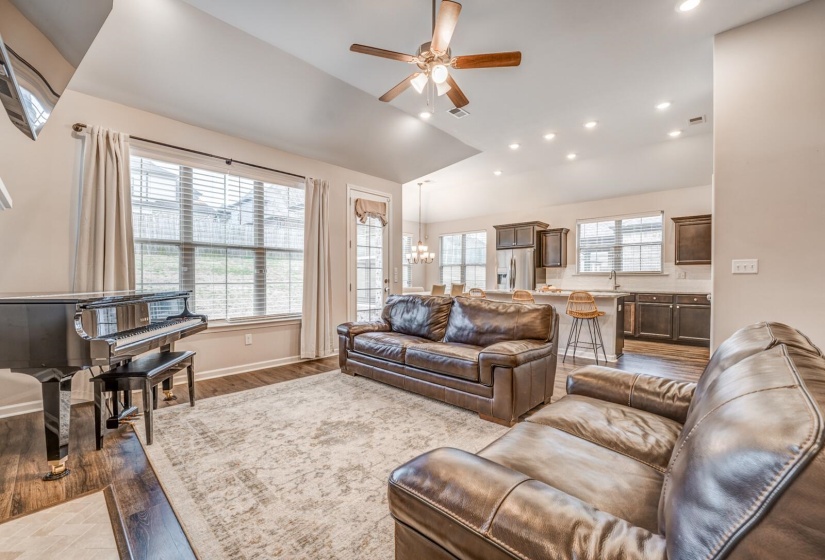 Living area featuring a ceiling fan, light wood finished floors, suspended lighting, and lofted ceiling
