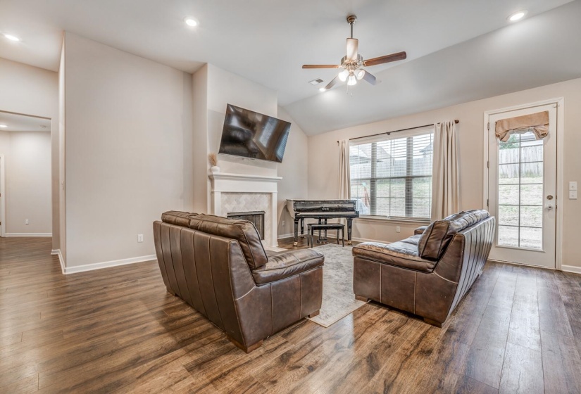 Living area with ceiling fan, dark wood-style flooring, vaulted ceiling, a fireplace, and recessed lighting