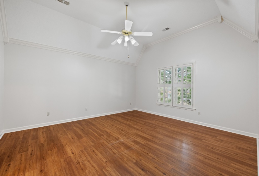 Spacious room featuring vaulted ceilings, wood-finish flooring, and white plantation shutters